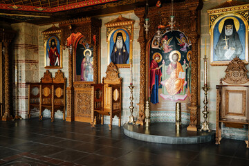 Meteora, Greece. 9.9.2025:  Interior of a traditional Eastern Orthodox monastery showing richly decorated iconostasis with religious paintings, carved wooden chairs, and ornate candle holders. 