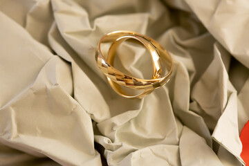 Paper Wedding Anniversary &ndash; Artistic Still Life. Artistic close-up of gold wedding rings on paper surface with shallow depth of field and warm accents, combining minimalism and emotional symbolism.