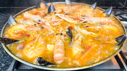 Spanish seafood paella with prawns, crayfish, and mussels bubbling in a pan