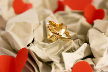 Wedding Rings on Paper Background &ndash; Paper Wedding Anniversary. Delicate composition of gold wedding rings on soft paper background with light shadows and neutral tones, symbolizing fragility