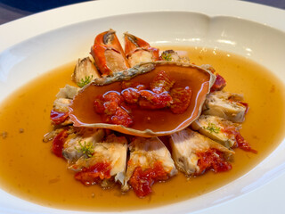 Exquisite seafood dish featuring fresh crab meat and crab roe artfully arranged in a shallow broth. The vibrant orange crab claws and rich roe contrast beautifully with the clear golden sauce