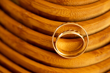 Minimal Gold Wedding Rings on Wood &ndash; Marriage Anniversary. Minimalistic composition of gold wedding rings on smooth wooden background with balanced light and shadows, emphasizing harmony 