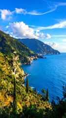 Coastal landscape with blue sea, green hills, and a winding road