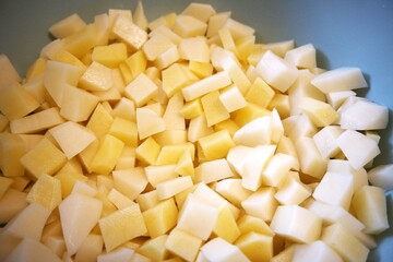 Freshness raw potatoes cut into cubes in a bowl, prepared for cooking or baking.