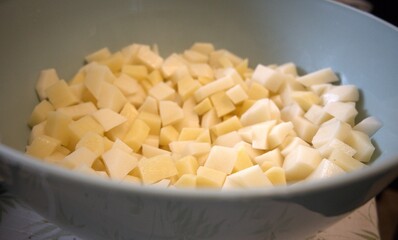 Freshness raw potatoes cut into cubes in a bowl, prepared for cooking or baking.