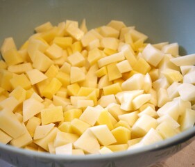 Freshness raw potatoes cut into cubes in a bowl, prepared for cooking or baking.