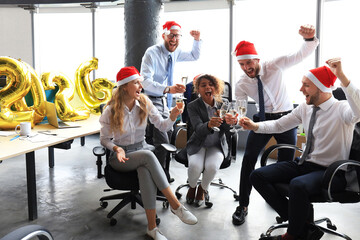 Business people are celebrating holiday in modern office drinking champagne and having fun in coworking. Merry Christmas and Happy New Year 2026.