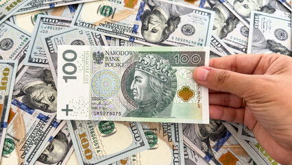 Hand Holding Polish Zloty Banknote Over US Dollar Bills – Currency Exchange and Finance Concept