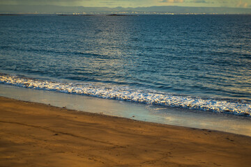 Golden sandy beach with gentle ocean waves at sunset