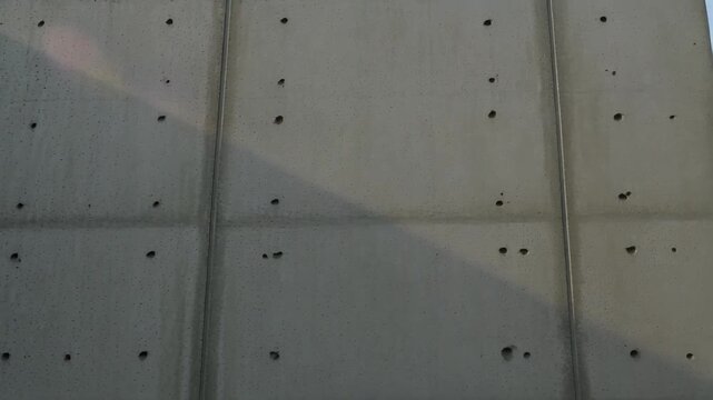 Modern brutalist concrete wall texture with shadow patterns and light reflections, architectural detail