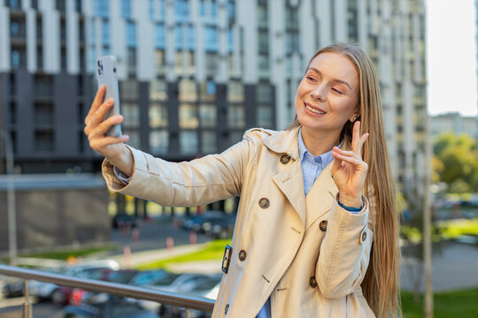 Mature businesswoman blogger taking selfie on smartphone, communicating video call online with subscribers recording stories for social media vlog outdoors. Girl standing on urban downtown street. - Powered by Adobe