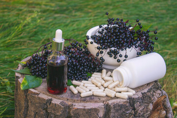 Different forms of natural elderberry medicine. Liquid extract in a bottle and capsules. Immunity
