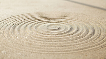 The photograph features concentric circles drawn in beige sand, creating a ripple-like pattern in the center, enhancing calmness, balance, and zen garden aesthetics.