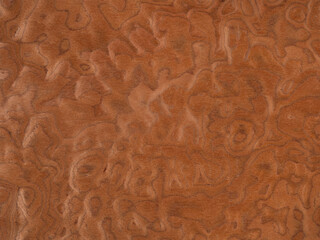 Swirls of auburn and cinnamon on a polished veneer wood surface