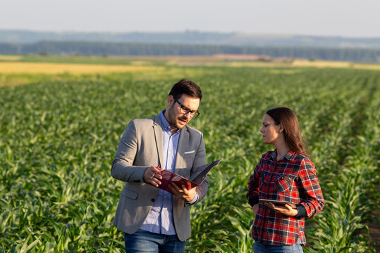 Farmer woman and businessman discussing crop progress in open field