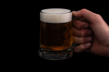 Dark beer in glass mug on black background – studio glassware