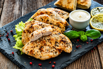 Fried chicken fillets with mayonnaise and pita bread on wooden table