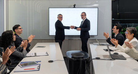 Two business leader shake hand in a modern conference room while colleague applaud. The atmosphere is positive, reflecting a successful partnership agreement.