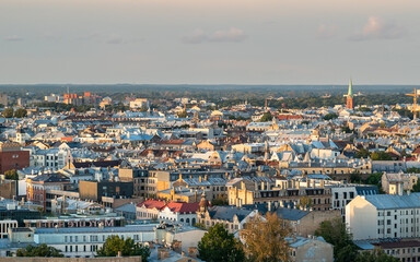Panoramic aerial photo of a European city with historic buildings and church towers under soft daylight. Urban skyline with classic architecture and rooftops seen from above.