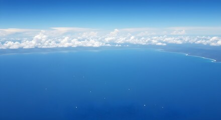 Fototapeta premium Aerial view of tranquil deep blue ocean with distant green landmass under bright sky