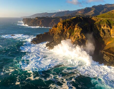 Dramatic aerial view of ocean waves crashing against rugged coastline cliffs at sunset