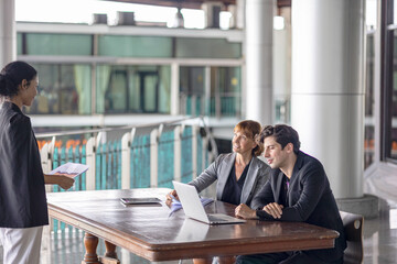 Conversation or group discussion among business team members from different generations, cultures, and diverse ethnicities outside of the main office. Group of people use computer to get information