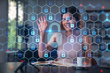 Woman interacting with digital padlock icons on hexagonal interface representing cybersecurity concept in modern office background setting.