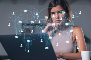 Woman using laptop with global email network concept shown on transparent digital world map background.