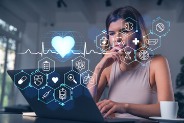 Woman using laptop with futuristic medical interface icons and glowing heart on transparent background, representing healthcare technology concept..