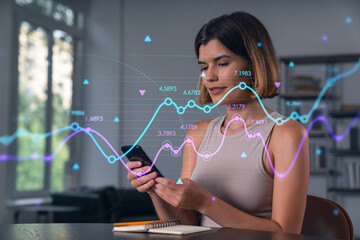 Woman analyzing financial data on smartphone with futuristic economic graph overlay in modern office background, concept of digital finance and analytics.