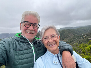 Portrait of happy elderly couple embrace  on a mountain excursion in La Gomera island expressing happiness and freedom. Senior man and woman looking at camera smiling
