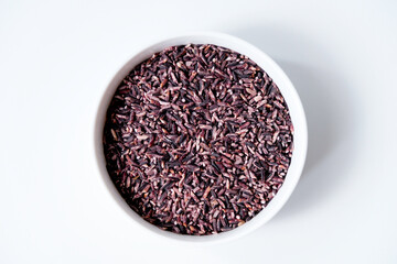 A bowl of black sticky rice grains isolated on white background