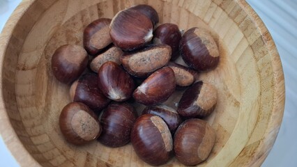 Fresh chestnuts (Castanea sativa) in a bamboo bowl — autumn close-up showing glossy texture and rustic styling, ideal for recipes, farmers markets and culinary visuals.