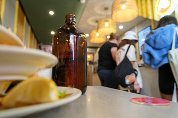 Casual coffee shop interior with drinks and food on the table, customers in the background.
