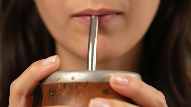 Woman Drinking Mate From a Traditional Gourd Using a Metal Bombilla, Close-Up on Mouth and Hands