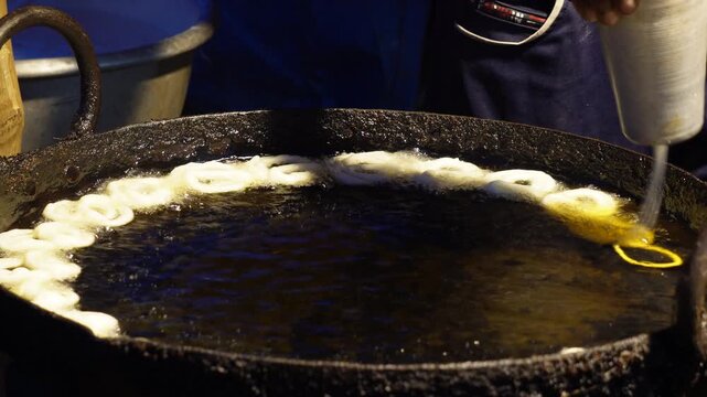jalebis being fried in a large pan