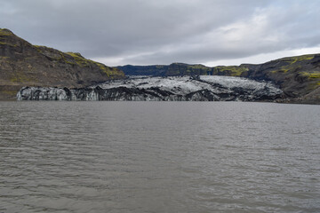 Glacier and lake below it, mountain landscape in cloudy weather, nature