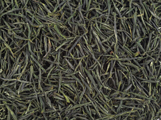 Dry green tea leaves as background, top view. Close-up.
