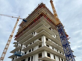 High-rise skyscraper under construction with cranes and scaffolding. Modern urban development in progress.