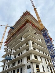 High-rise skyscraper under construction with cranes and scaffolding. Modern urban development in progress.