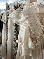 White ruffled dresses on hangers in a fashion boutique, highlighting elegant textile details