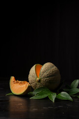 View of an open green cantaloupe melon, black background, vertical, with copy space