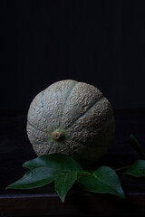 Close-up of green cantaloupe melon, black background, vertical, with copy space