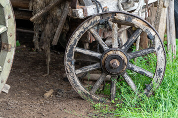 Old wooden wagon wheel on the ground in the field. Selective focus.