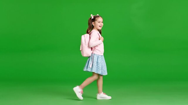 Young girl walking with backpack on green screen