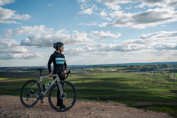 Obraz premium Young woman cyclist enjoying scenic view from hilltop with gravel bike