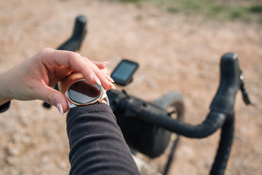 Young woman cyclist checking smartwatch during gravel bike ride