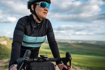 Naklejka premium Young woman cycling on gravel path, enjoying scenic countryside view