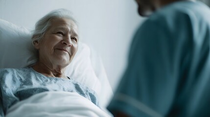 Obraz premium Elderly patient smiles warmly while looking at a caregiver in a bright hospital room