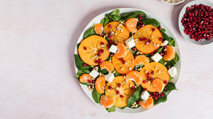 Winter salad. Fresh persimmon and citrus salad with spinach, feta, and pomegranate. Copy space.